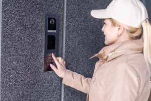 blondynka młoda kobieta w budynku telefon domofon na ulicy.