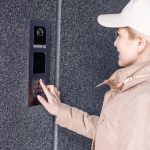 blondynka młoda kobieta w budynku telefon domofon na ulicy.