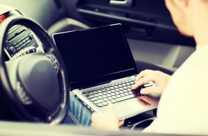 koncepcja transportu i pojazdu - mężczyzna używający laptopa w samochodzie
