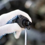 Repair under the hood of a car with gloved hands and a screwdriver auto mechanic at workxA