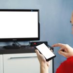 Zrelaksowany mężczyzna ze smartfonem podłączonym do telewizora Pusty ekran biały ekran Formularz informacji Ekran telewizora bez informacji i treści Używanie smartfona do przesyłania informacji do telewizora