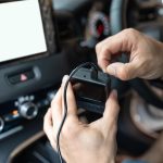 Ręka technika przygotowująca i instalująca rejestrator samochodowy z przednią kamerą w samochodzie