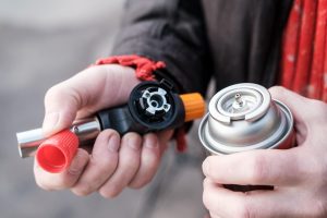 Przenośna butla gazowa do podróży w męskich rękach na rozmytym tle Zbliżenie