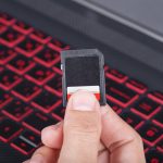 ręka trzyma kartę SD z laptopa