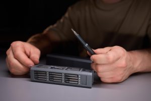 Osoba demonstrująca precyzję za pomocą narzędzi naprawiających skomplikowane elementy elektroniczne