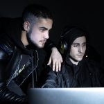 Portret młodych hakerów w pracy. Mężczyźni w zwykłych ubraniach, patrząc na ekran laptopa, pisząc. Hacking, koncepcja komputerowa