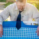 Przystojny mężczyzna w garniturze cierpi z powodu upału przy basenie