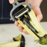 Bakłażan w kobiecych rękach obierania bakłażana nożem