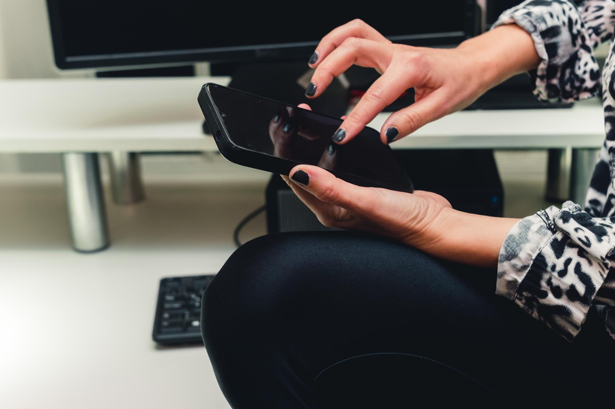 Kobiece ręce kaukaski za pomocą telefonu w biurze firmy