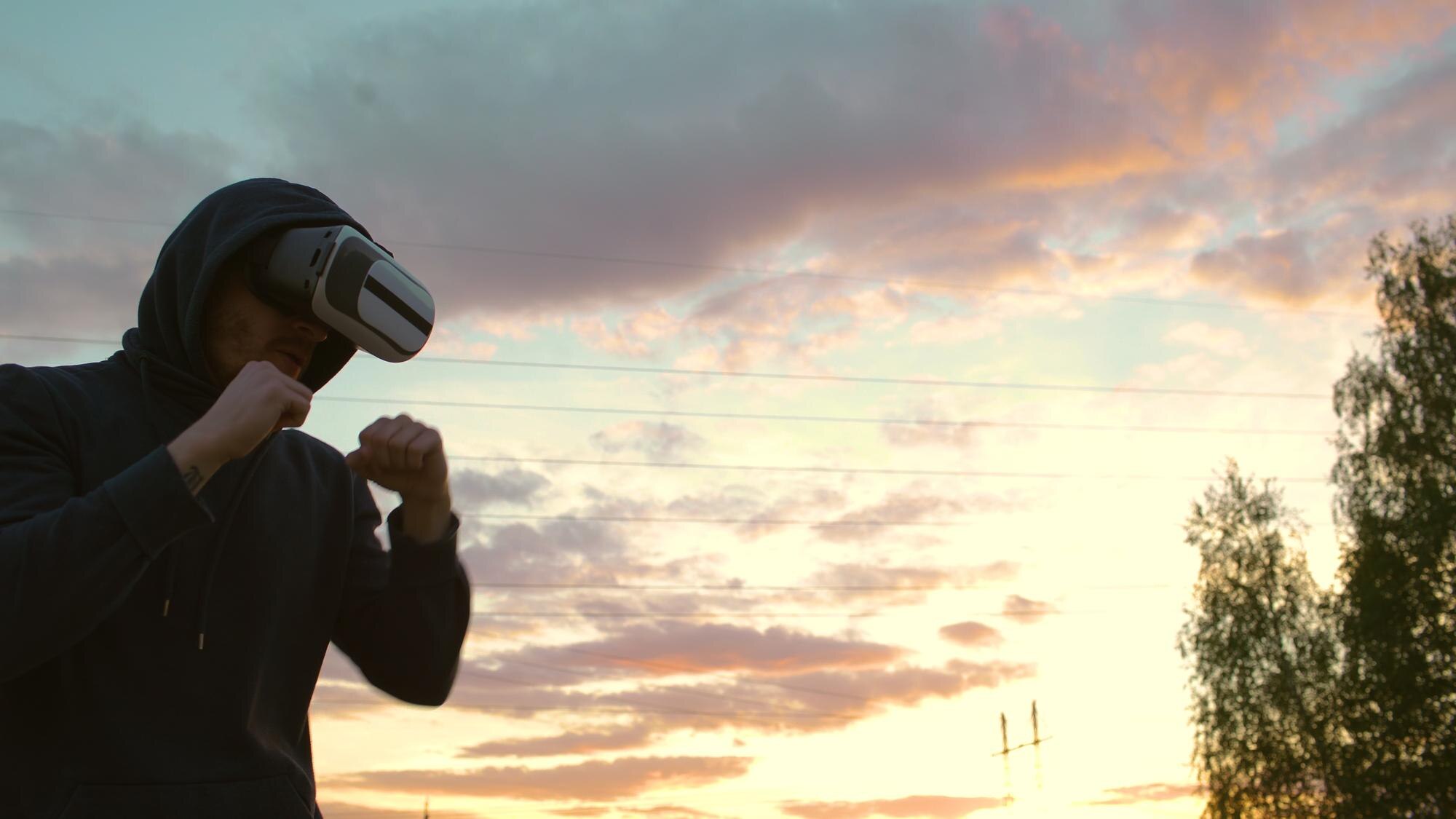 Sylwetka młodego boksera w treningu na zestaw słuchawkowy VR 360 do kopania w walce w wirtualnej rzeczywistości