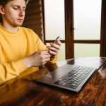 Facet pracuje w domku przy stole w pokoju z drewnianym wnętrzem używa smartfona