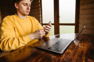 Facet pracuje w domku przy stole w pokoju z drewnianym wnętrzem używa smartfona