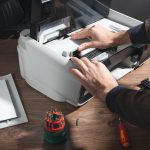 Kaukaski mężczyzna naprawiający drukarkę cyfrową