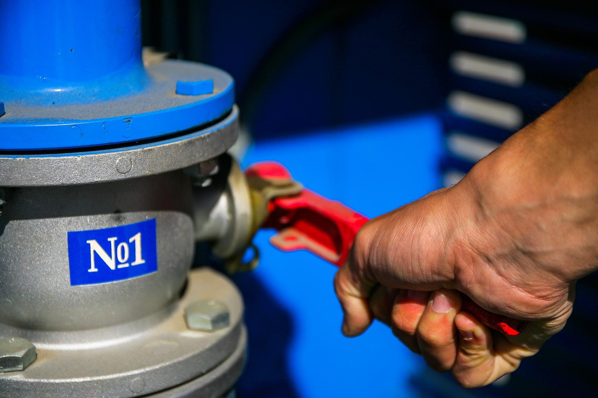 Męska ręka otwiera kurek gazu nr 1