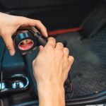 Ręka mechanika używająca taśmy klejącej do owijania drutu samochodowego do zainstalowania urządzenia