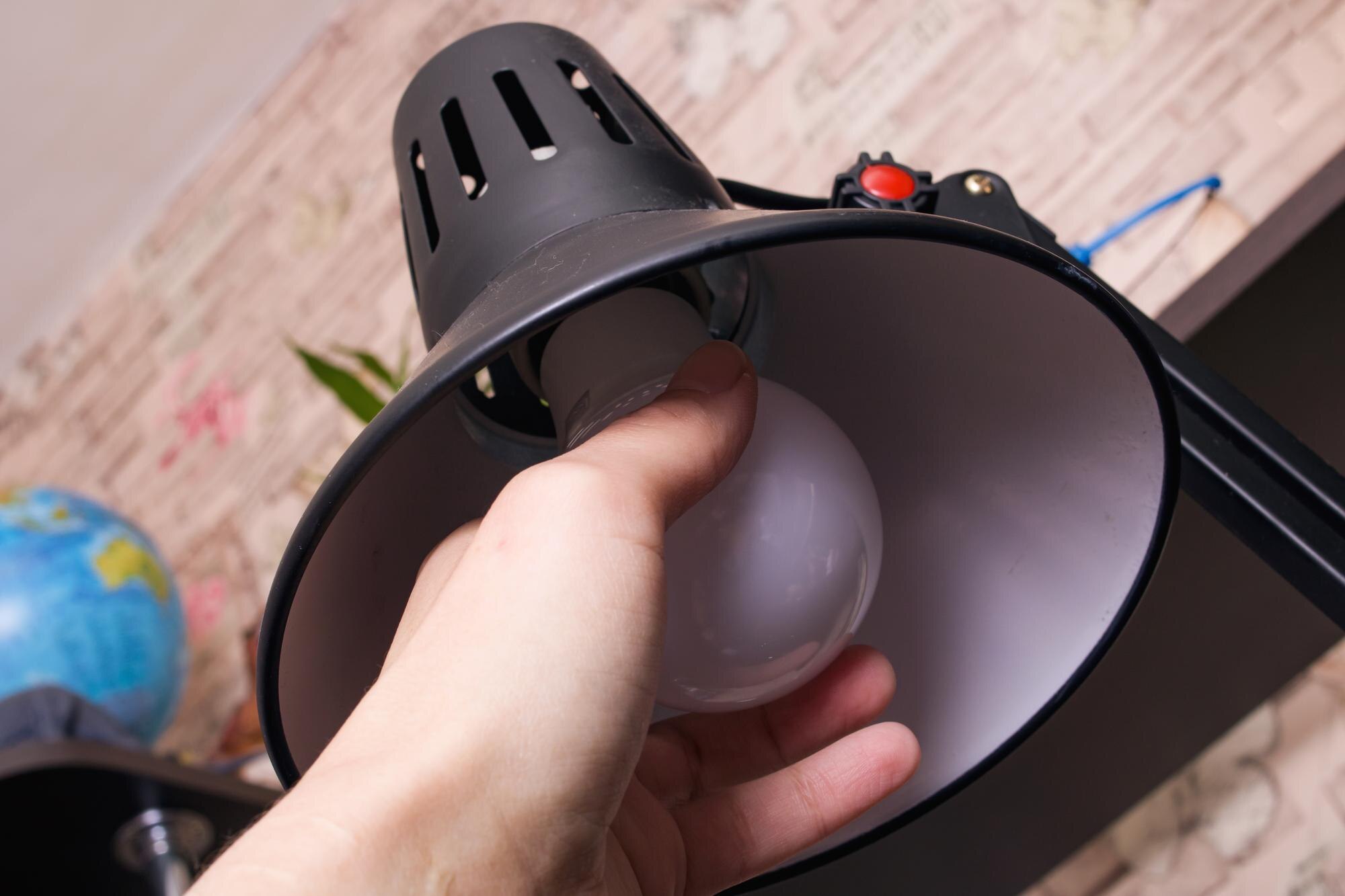 Ręka przekręca żarówkę w pokoju