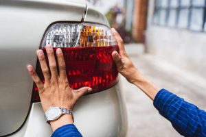 Bliska młody człowiek ręce mechanik samochodowy sprawdzanie światła tylnego Koncepcja serwisowania i naprawy samochodów