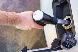 Ręka mężczyzny tankującego wężem w baku samochodu