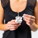 Bezprzewodowe słuchawki w rękach kobiet Koncepcja technologii przenośnej