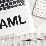 Tekst AML AntiMoney Laundering na notatniku i laptopie na drewnianym tle