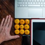 Mężczyzna położył mandarynki obok laptopa i tabletu
