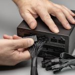 Nowy zasilacz do komputera stacjonarnego wraz z kompletem przewodów i kabli. Połączenie, męskie dłonie.