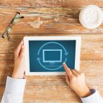 koncepcja biznesu, edukacji, ludzi i technologii - zbliżenie kobiecych dłoni wskazujących palcem i ponowne uruchamianie komputera typu tablet przy stole