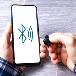 Mężczyzna łączący słuchawki bezprzewodowe z telefonem komórkowym