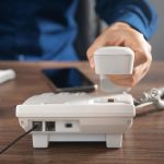 Biznesmen posiadający słuchawkę telefonu przy biurowym stole