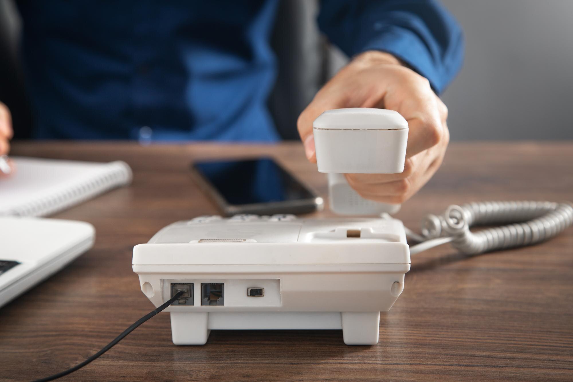 Biznesmen posiadający słuchawkę telefonu przy biurowym stole