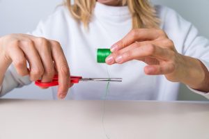 ręka z nożyczkami wycinanie nici, krawcowa, atelier, szycie, szycie ubrań, haftowanie