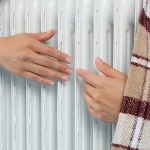 Kobieta w sezonie grzewczym grzeje ręce grzałką