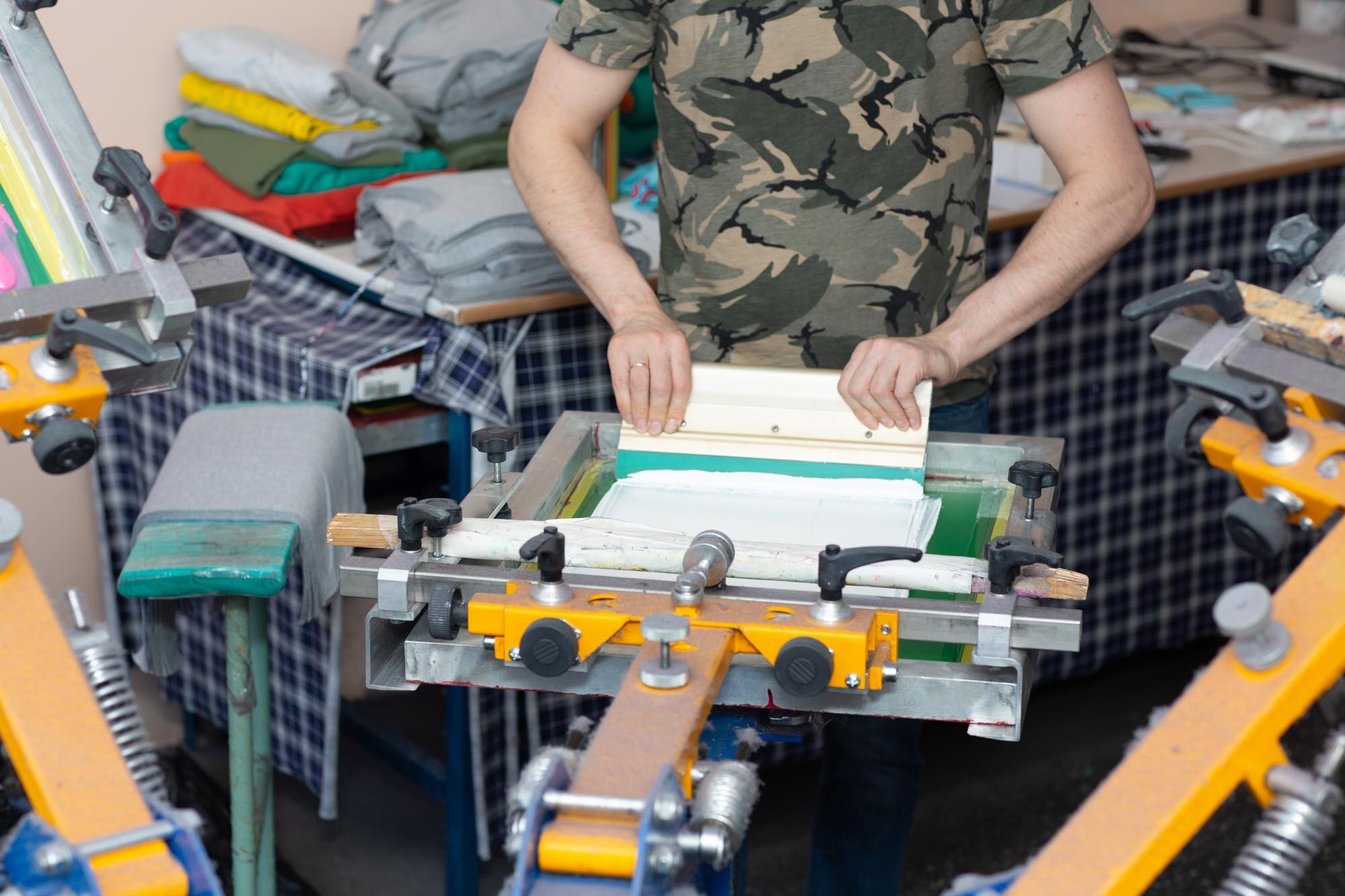 Aplikacja do drukowania zdjęć przez pracowników Proces sitodruku w sitodruku w fabryce odzieży Ściągaczka do ram i kolorowe farby plastizolowe