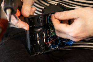 Zbliżenie męskich rąk, naprawiając ładowarkę. Praca z urządzeniami elektronicznymi