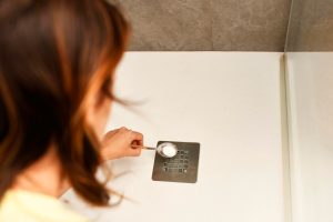 Kobieta z tyłu nasypuje tłoczek proszku pod prysznic lub sodę oczyszczoną do czyszczenia w wylocie wody