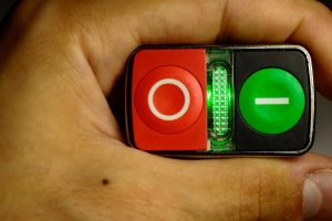 Dziecko trzymające w ręku mały starter. Czerwone i zielone przyciski do uruchamiania silnika.