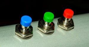 Małe kolorowe guziki na aluminiowej rurce - zbliżenie na zdjęcie. Obraz w tle.