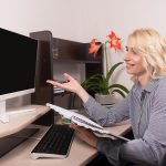 Uśmiechnięta kobieta siedzi przy biurku Praca w domu