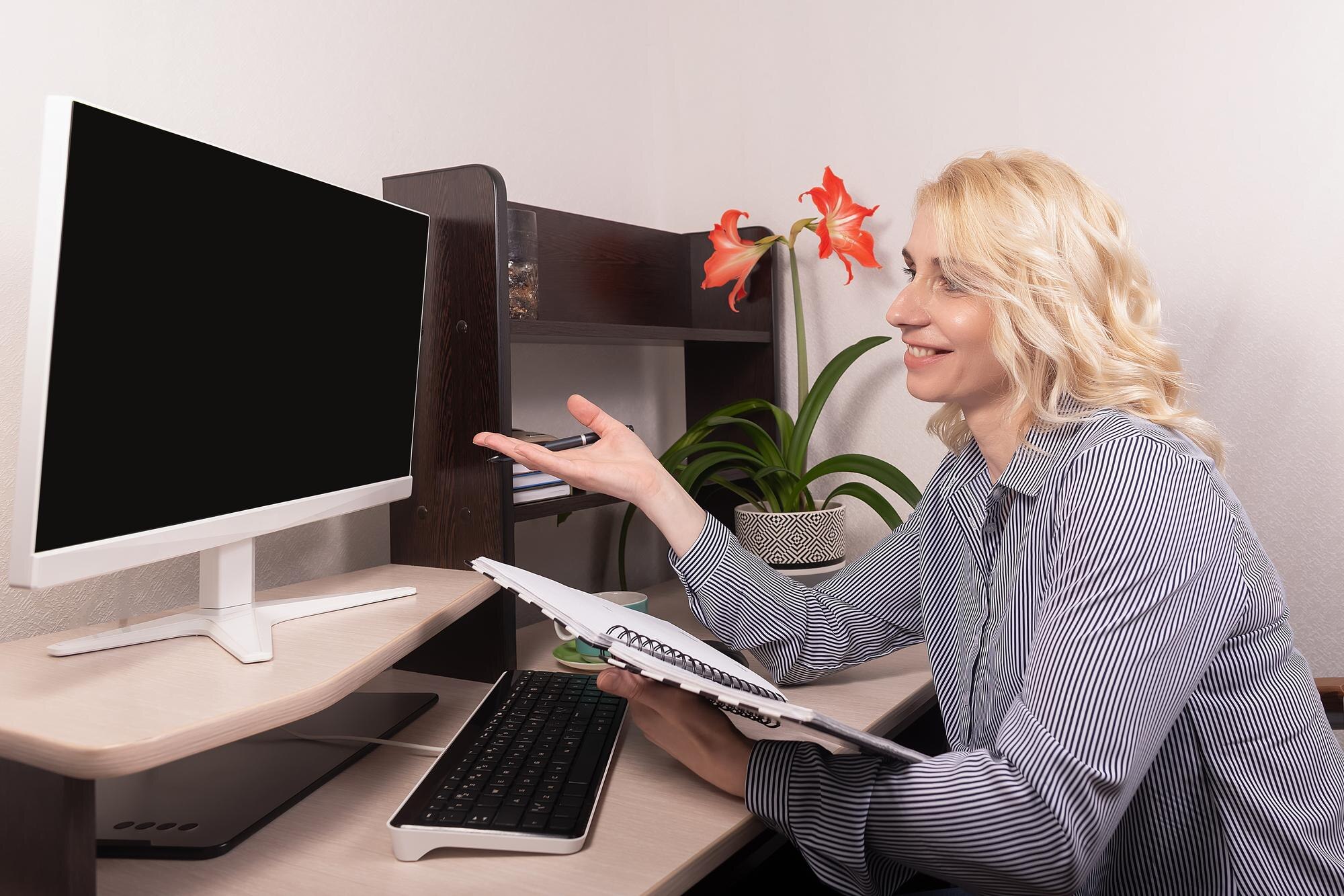 Uśmiechnięta kobieta siedzi przy biurku Praca w domu