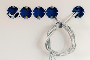 Ściana jest z jasnego tynku i posiada kilka odpływów Przygotowanie do zainstalowania odpływu Wystają przewody Instalacja gniazdek elektrycznych