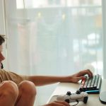 Chłopiec siedzi na stole z laptopem i monitorem, który mówi słowo na nim