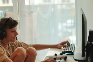 Chłopiec siedzi na stole z laptopem i monitorem, który mówi słowo na nim