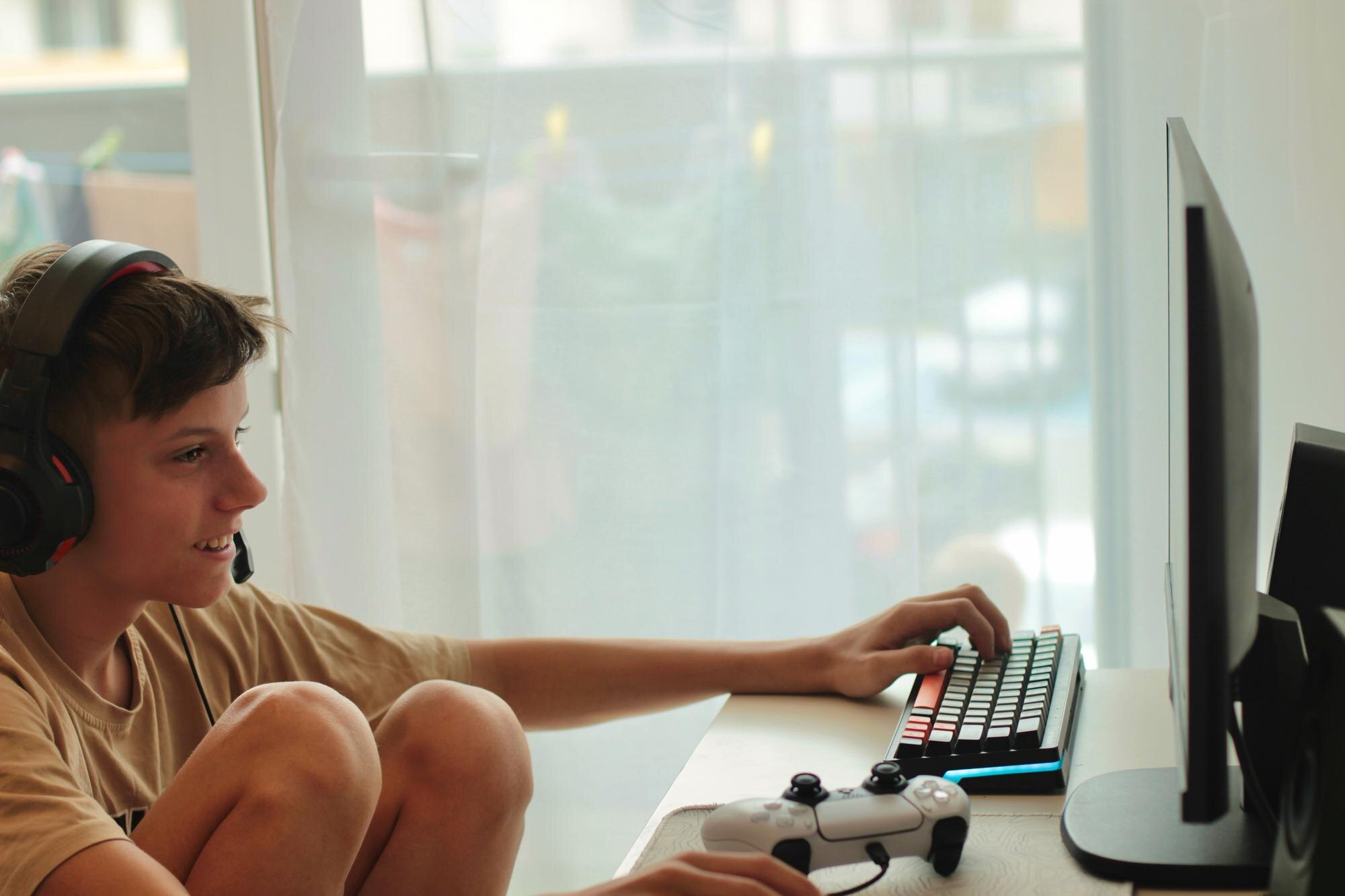 Chłopiec siedzi na stole z laptopem i monitorem, który mówi słowo na nim