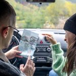 Mężczyzna i dama trzymający papierową mapę siedzący w samochodzie i patrzący na nią