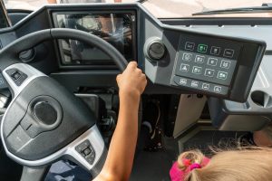 Zbliżenie dłoni dziecka na kierownicy autobusu Dziecko w kabinie samochodu Widok na kierownicę i deskę rozdzielczą nowego nowoczesnego autobusu Miejski transport publiczny