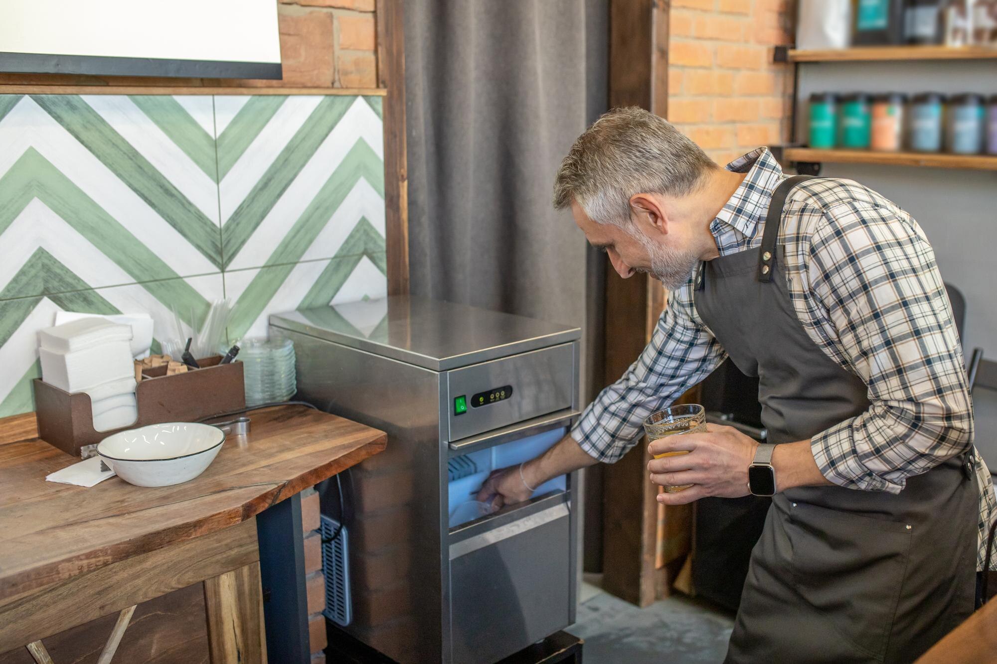Lód na sok. Mężczyzna w kraciastej koszuli bierze lód z lodówki