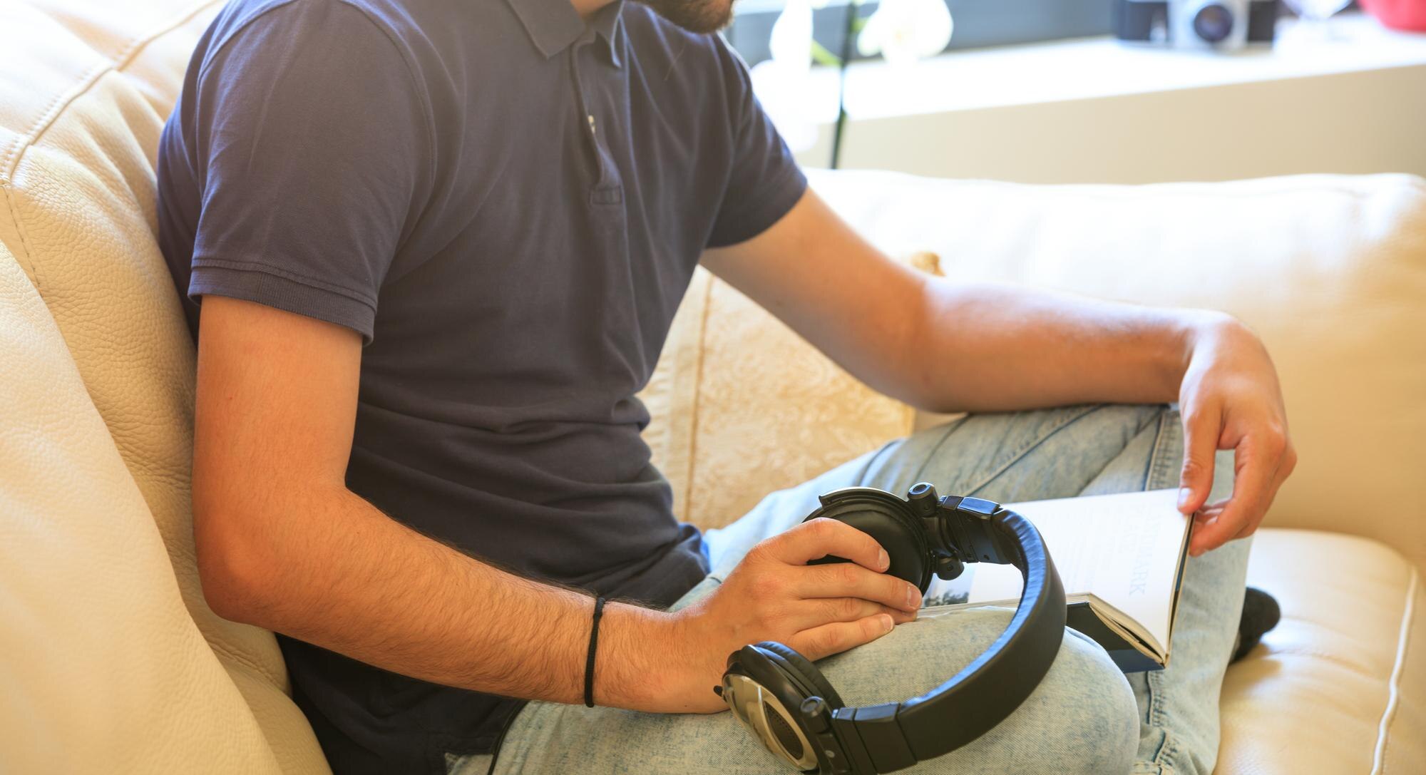 Mężczyzna czyta książkę siedząc na kanapie w domu