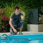 Technik konserwacji basenu analizuje próbkę wody obok basenu otoczonego zielenią i