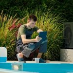 Technik basenu używający tabletu przy basenie otoczonego zielenią i skoncentrowanego pojemnika chemicznego