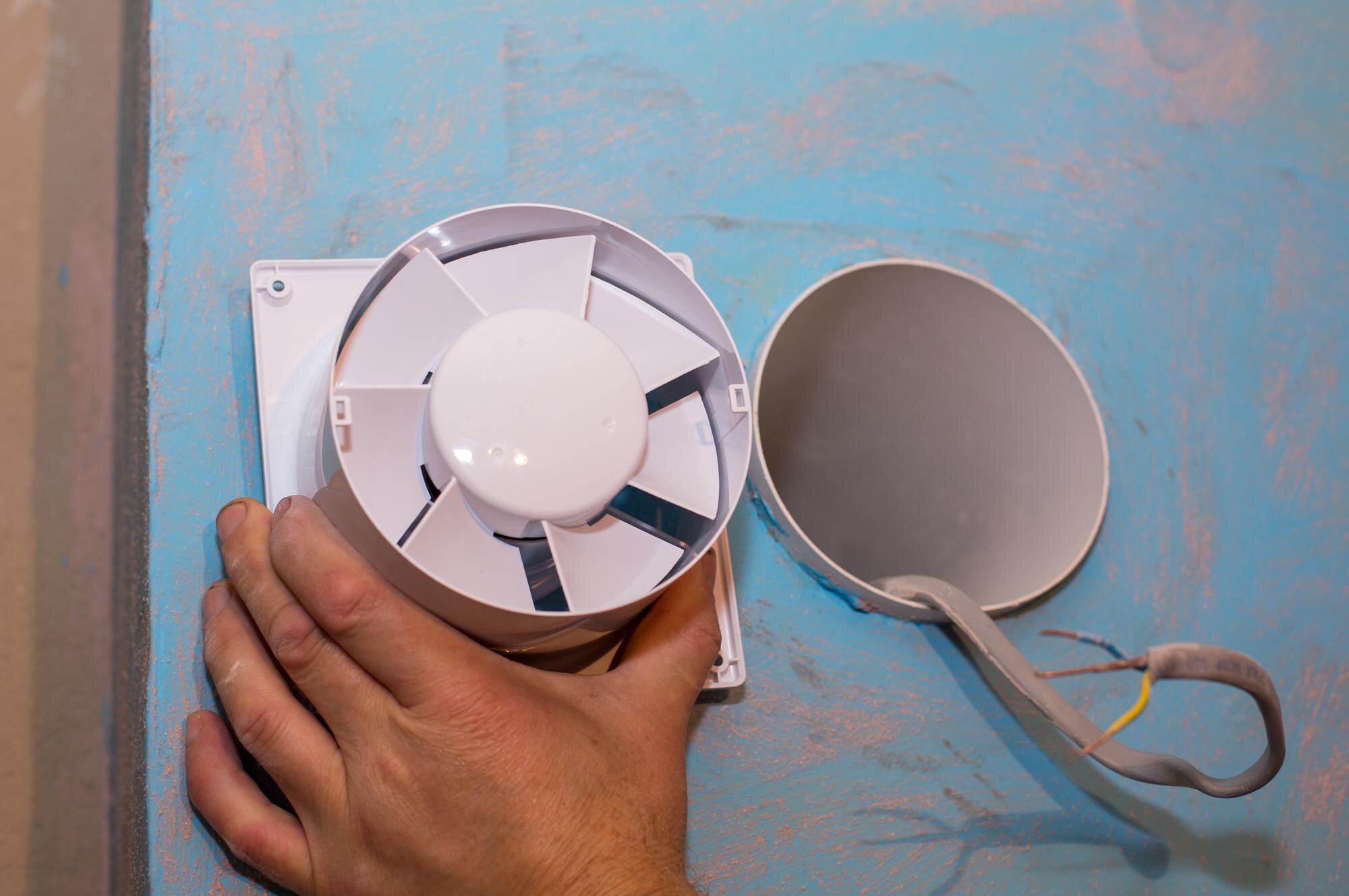 Człowiek instaluje wentylator w łazience proces renowacji przewody w rękach konserwacja prace remontowe renowacja w mieszkaniu